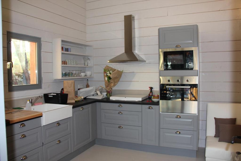 une cuisine avec des armoires blanches et un four à plaques de cuisson dans l'établissement Gîtes "Les Cabanes de Carelle" entre Camargue et Cévennes, à Aspères