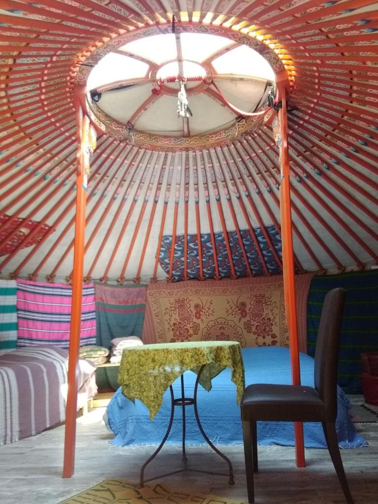 Cette chambre comprend une yourte avec une chaise et une table. dans l'établissement Les yourtes de Bascot, à Vaylats
