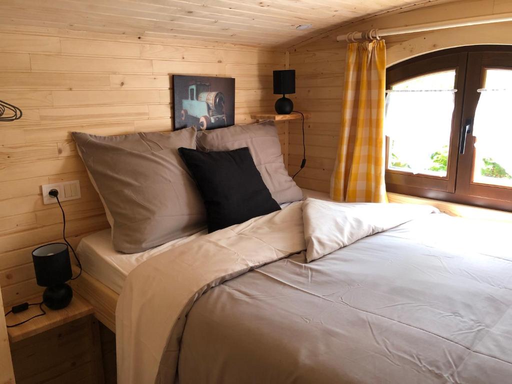 une chambre avec un lit dans une cabane en rondins dans l'établissement La Roulotte d'Emilie et son jacuzzi privé, à Beurlay