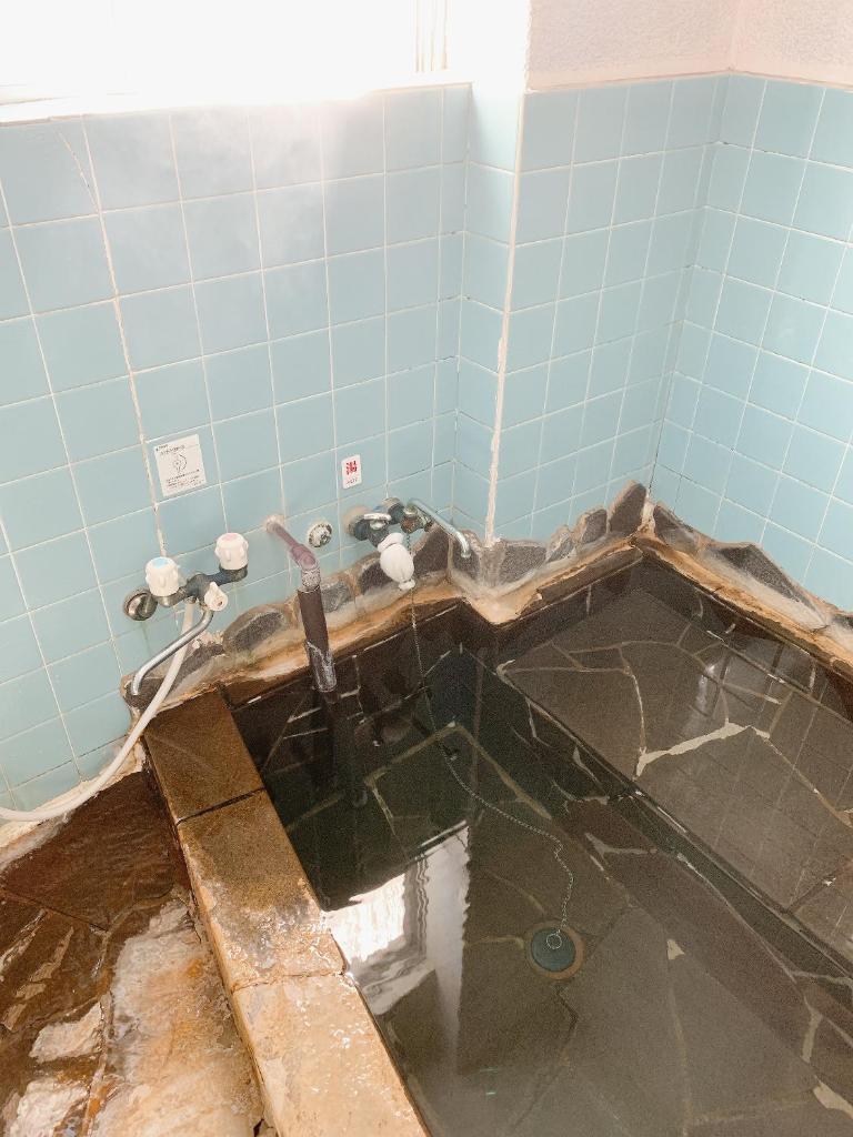 La salle de bains est pourvue d'une baignoire avec de l'eau. dans l'établissement Minshuku Sumiya, à Tanabe