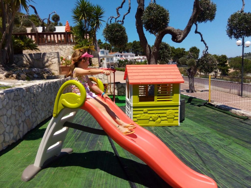 une petite fille sur un toboggan dans une aire de jeux dans l'établissement Villa dei pini, à Vieste