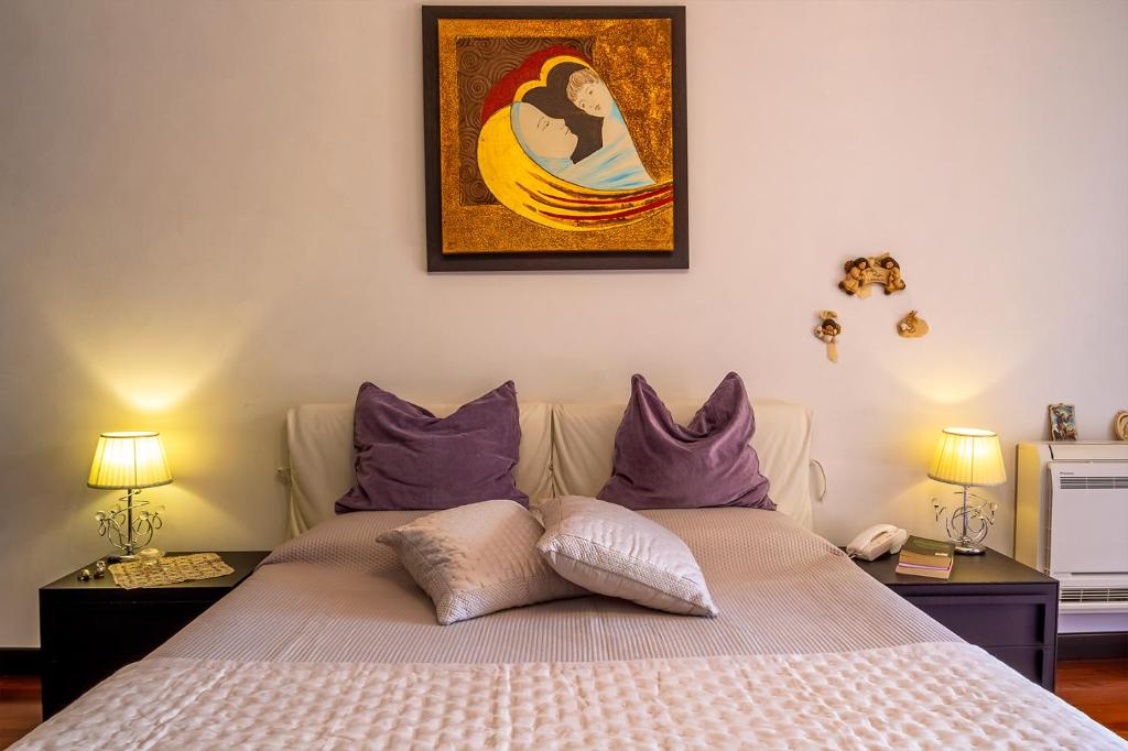 - une chambre avec un lit doté d'oreillers violets et d'un tableau dans l'établissement Villa Magdalena, à Aci SantʼAntonio