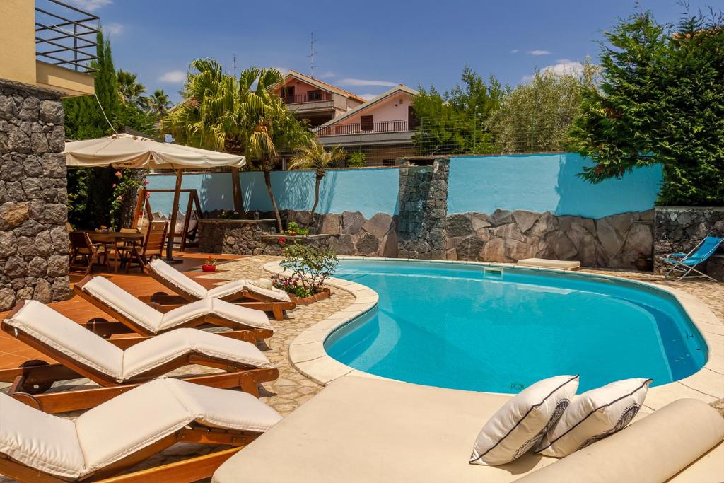 une piscine avec des chaises longues et une piscine dans l'établissement Villa Magdalena, à Aci SantʼAntonio