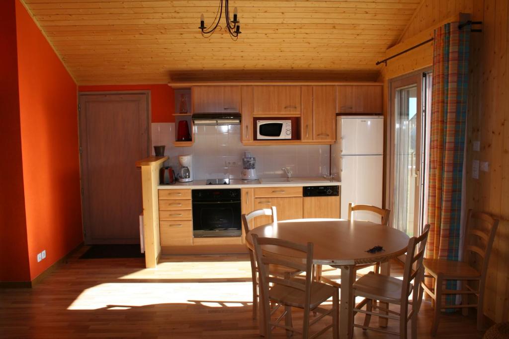 - une cuisine avec une table, une table et des chaises dans l'établissement Chalets de Trémontagne 3 étoiles, à Prénovel