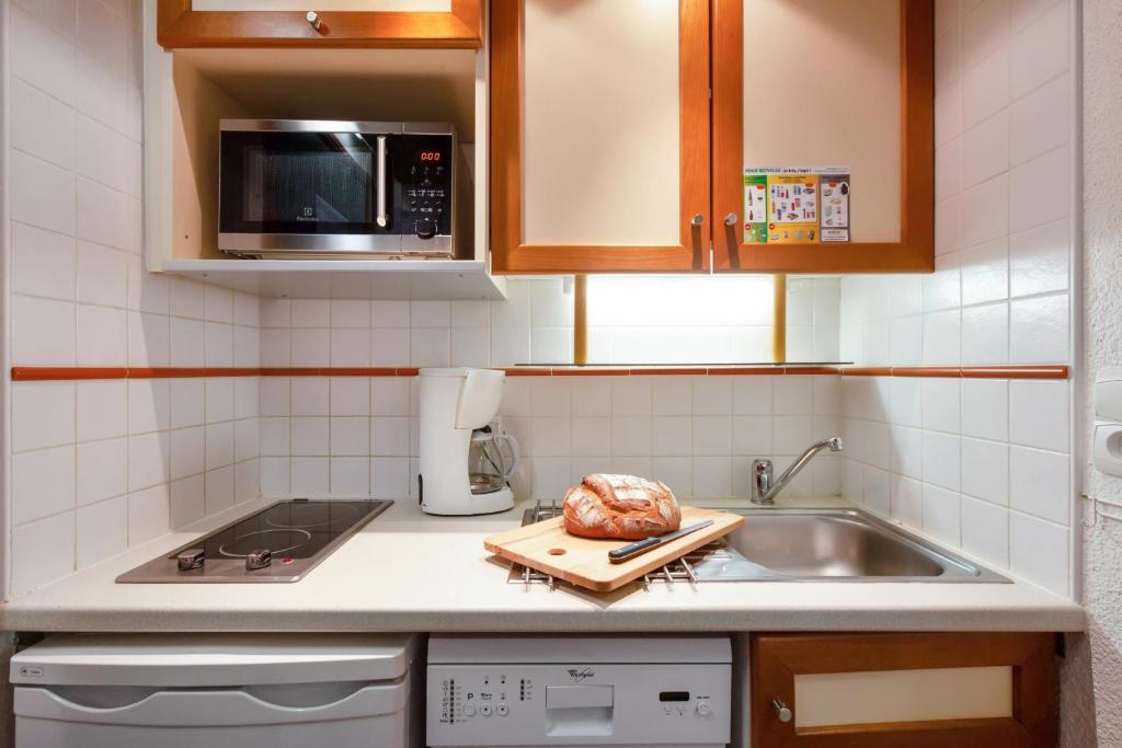 une cuisine avec un évier et un comptoir avec une dinde sur une planche de découpe dans l'établissement Résidence Pierre & Vacances Le Gypaète, à Val Thorens