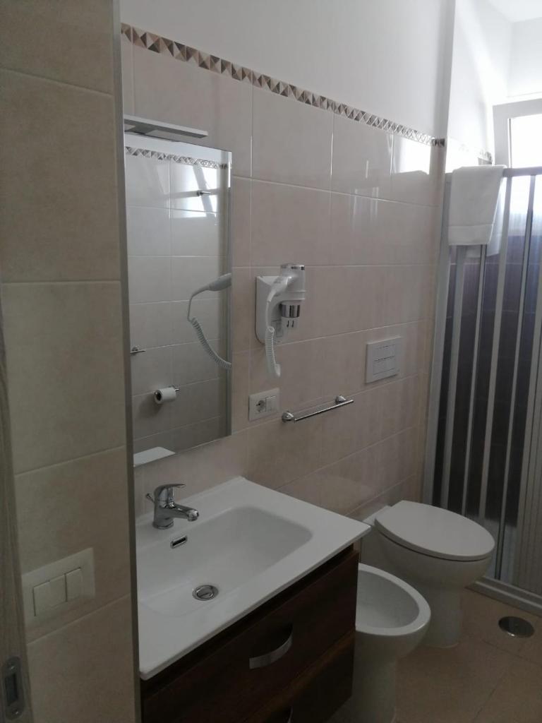 une salle de bain avec un lavabo, des toilettes et un miroir dans l'établissement Hotel Tirreno Formia, à Formia