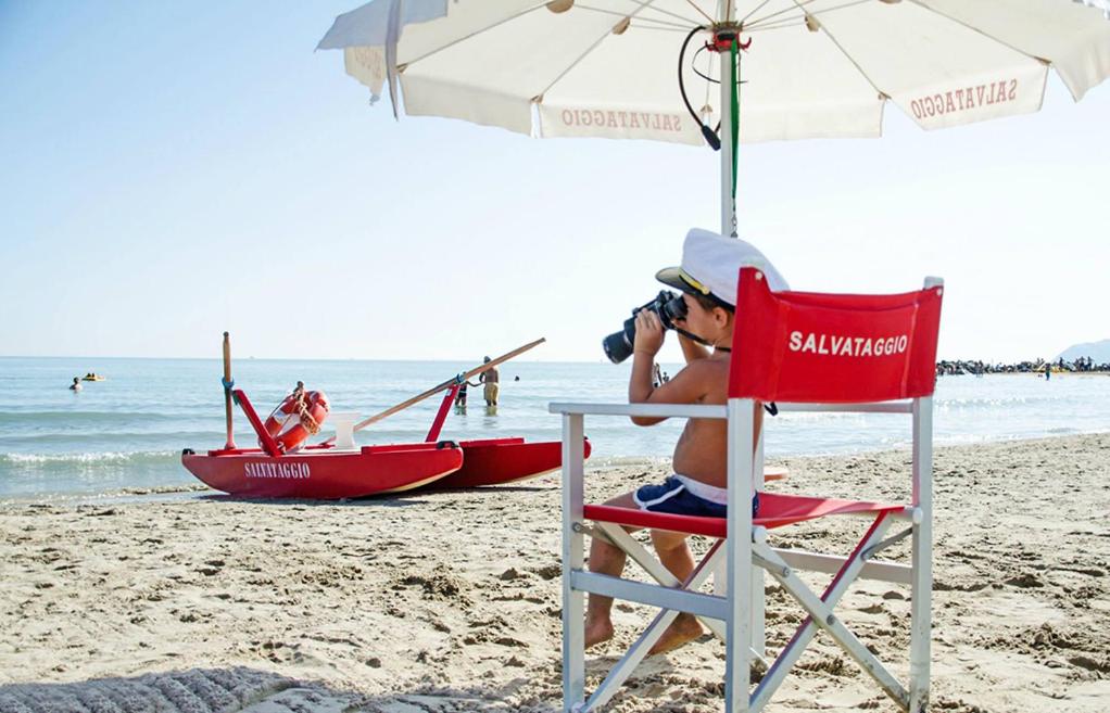 une personne assise sur une chaise de plage avec une caméra dans l'établissement Hotel Atlantic Riviera Mare, à Misano Adriatico 54 autres photos