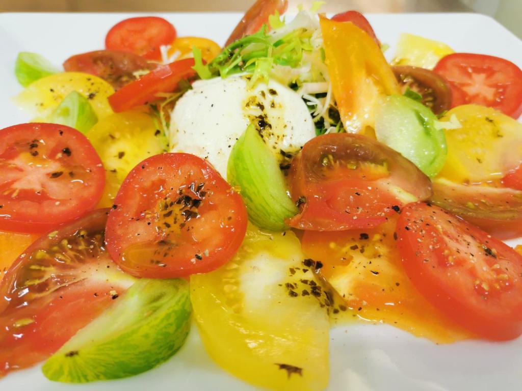 une assiette de denrées alimentaires contenant des tomates et d’autres légumes dans l'établissement Hôtel Le Christania, à Bellevaux 37 autres photos