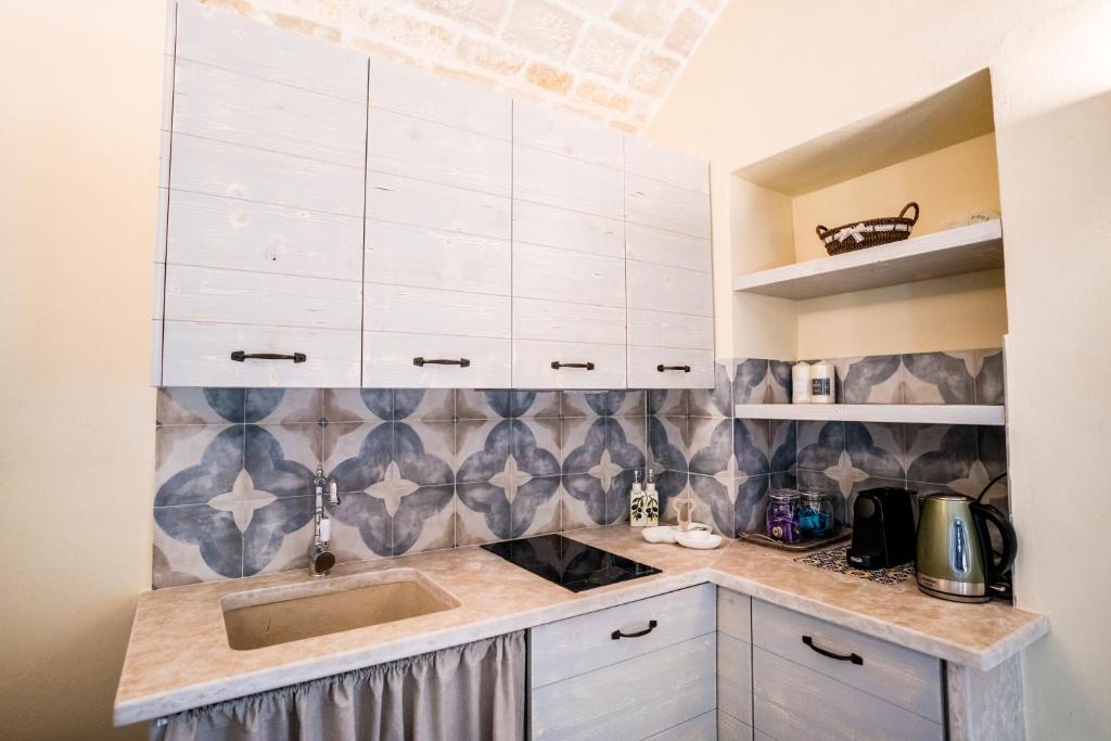 une cuisine avec des armoires blanches et un évier dans l'établissement Trulli Ad Maiora, à Alberobello