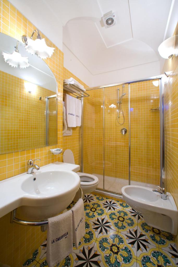 une salle de bain avec deux lavabos et une douche et deux toilettes dans l'établissement La Caravella di Positano - Relais, Beach & Residences, à Positano 59 autres photos