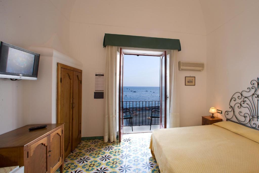 une chambre avec un lit et une vue sur l'océan dans l'établissement La Caravella di Positano - Relais, Beach & Residences, à Positano