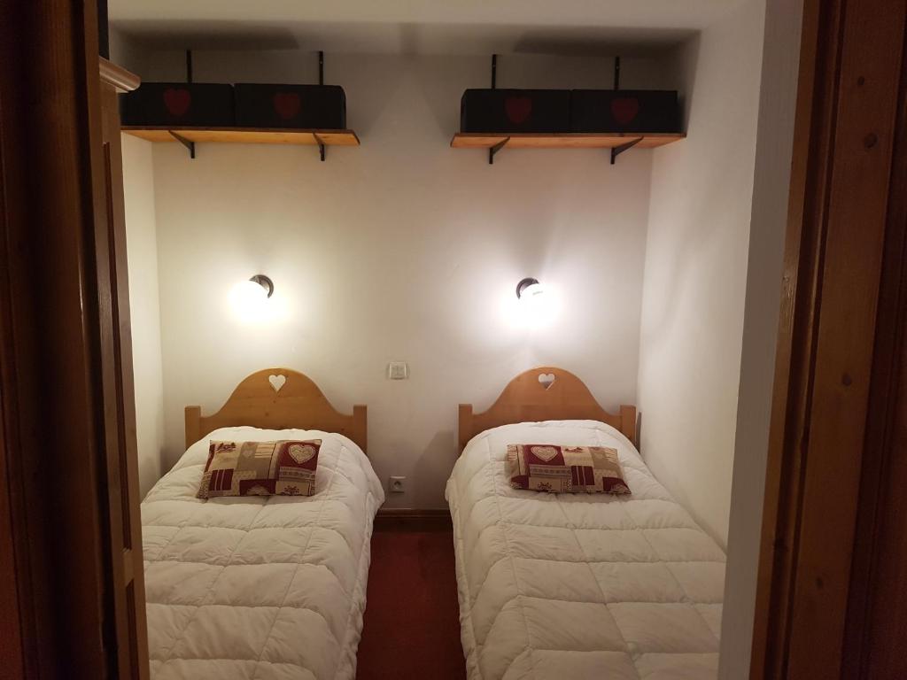 deux lits dans une petite pièce aux murs blancs dans l'établissement Appartement Le Pic Blanc, à Oz 28 autres photos