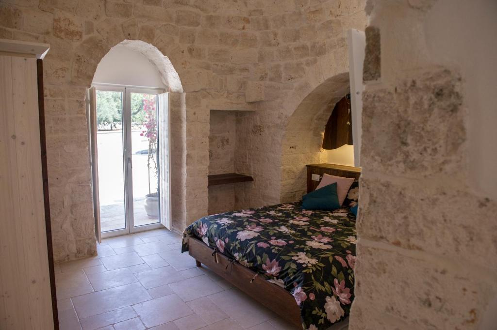 une chambre avec un lit dans un mur de pierre dans l'établissement Trulli Pietraviva with Pool, à Santa Lucia
