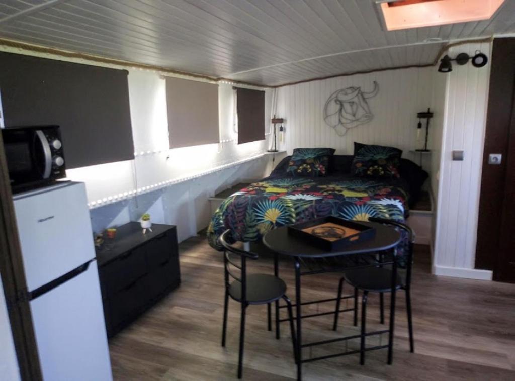 Cette chambre comprend un lit, une table et une cuisine. dans l'établissement Séjour atypique et insolite sur notre péniche La Coradine avec grand spa, à Aigues-Mortes 13 autres photos