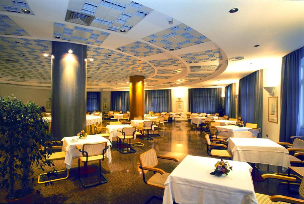 une salle à manger avec des tables et des chaises blanches dans l'établissement Grand Hotel Palace, à Terracine 27 autres photos