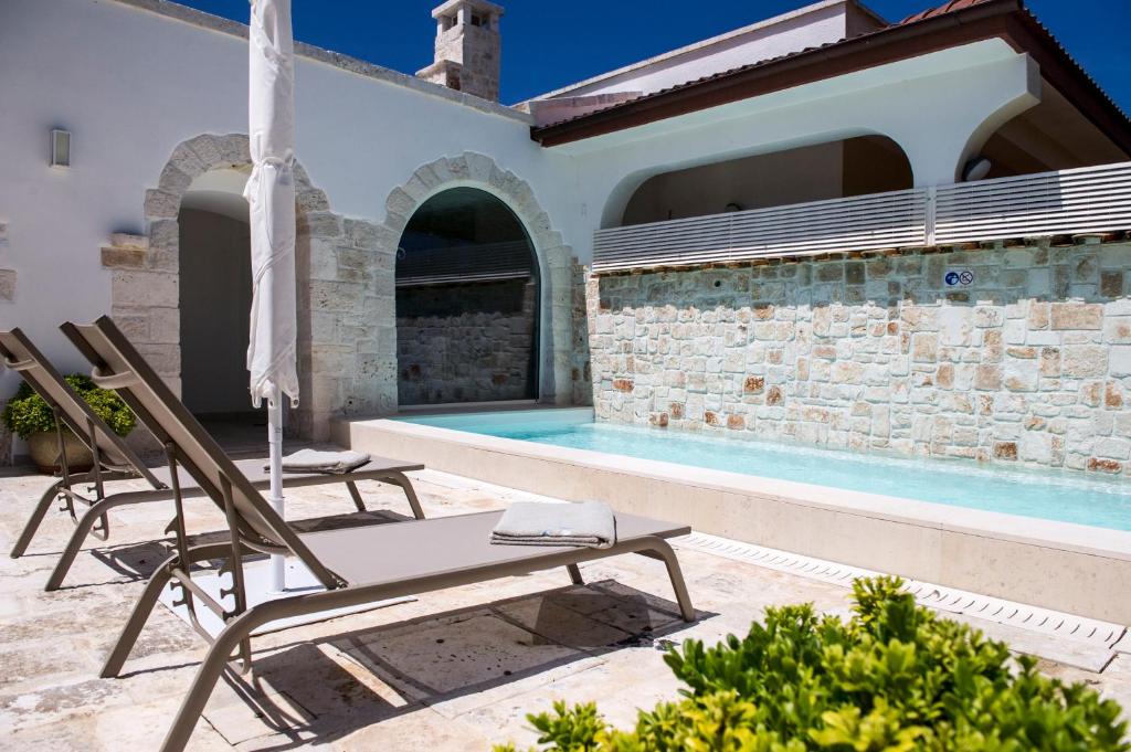 un patio avec deux chaises et une piscine dans l'établissement Trulli Pietraviva with Pool, à Santa Lucia