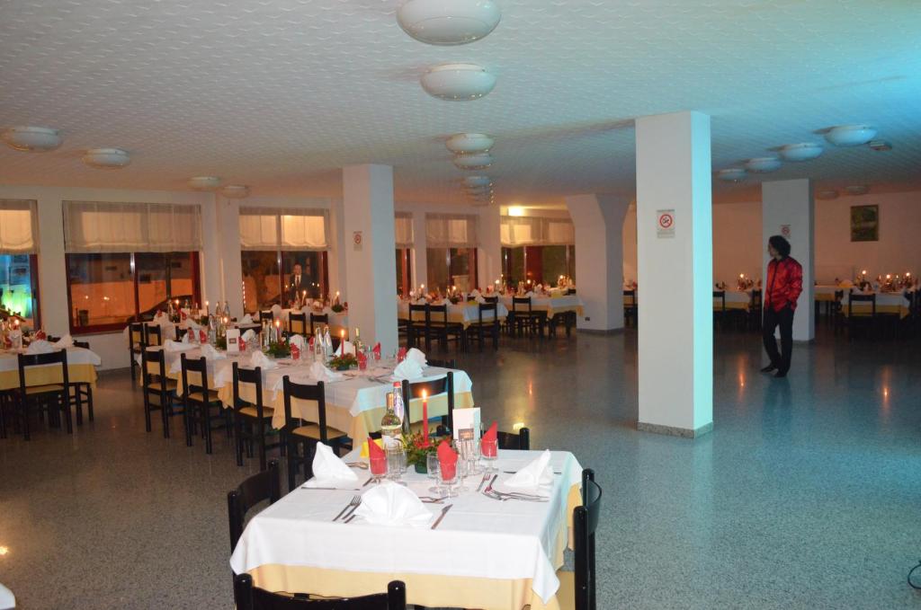 une salle de banquet avec des tables et des chaises blanches dans l'établissement Hotel Palmarosa, à Roseto degli Abruzzi