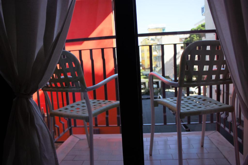 deux chaises assises sur un balcon regardant par une fenêtre dans l'établissement Hotel Neps, à Lido di Jesolo 38 autres photos