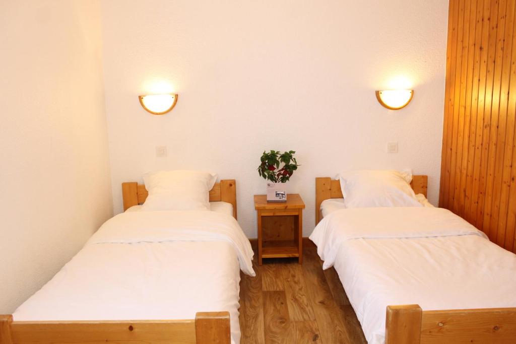 deux lits dans une chambre avec des draps blancs dans l'établissement Résidence Saboia B13 Clés Blanches Courchevel, à Courchevel