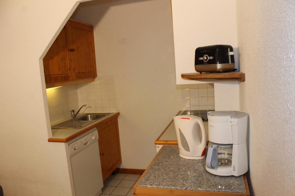 Il comprend une petite cuisine avec un évier et une cafetière. dans l'établissement Résidence Saboia B13 Clés Blanches Courchevel, à Courchevel 9 autres photos