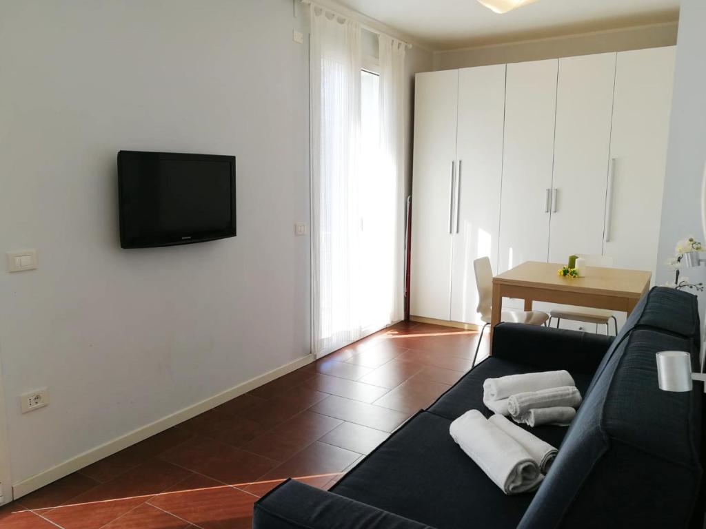 - un salon avec un canapé et une télévision murale dans l'établissement Margherita Rimini - Appartamenti al Mare, à Rimini