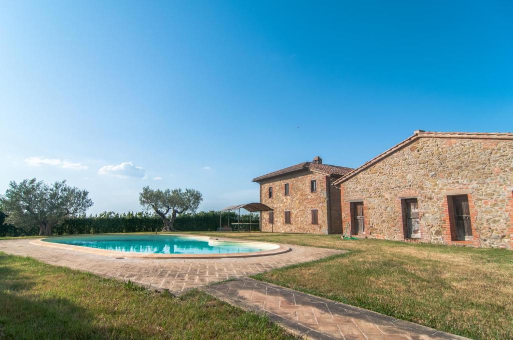- un ancien bâtiment en pierre avec une piscine en face dans l'établissement Cottage Casaglia, à Paciano