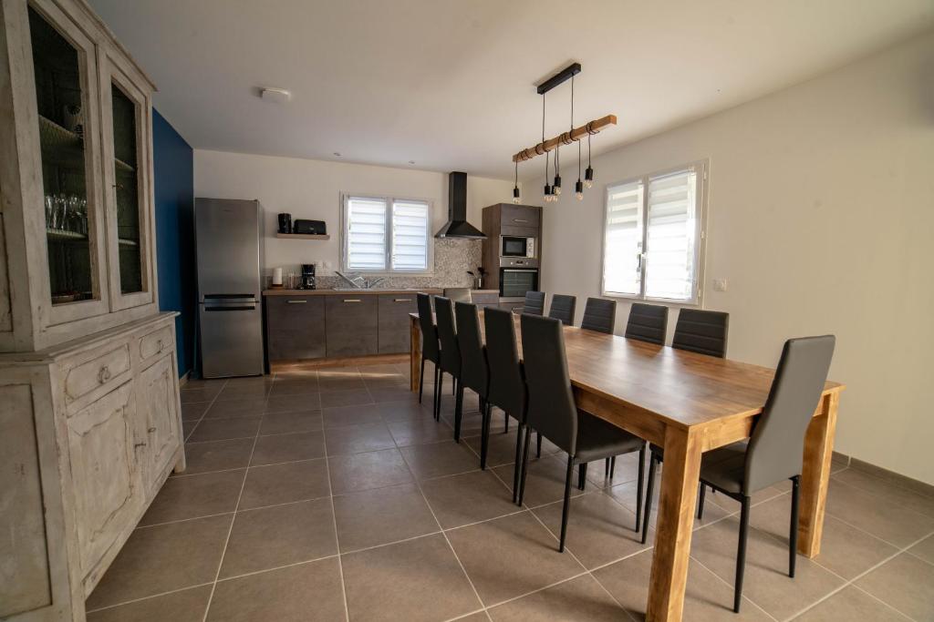 une cuisine et une salle à manger avec une table et des chaises en bois dans l'établissement Gite LES BOUCHES ROUGES avec piscine privée, à Vesseaux