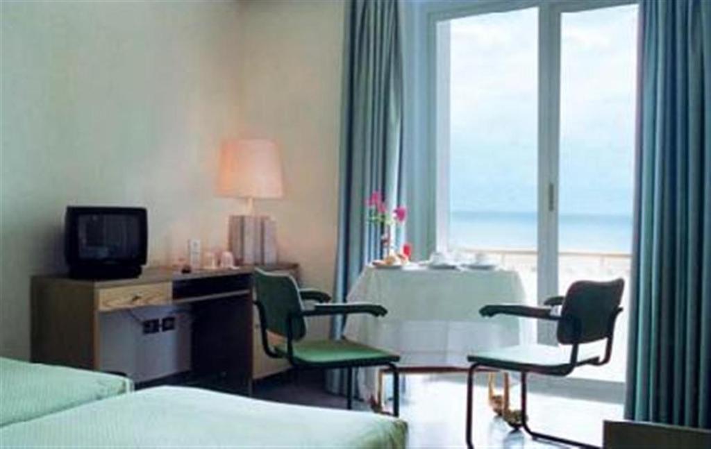 une chambre d'hôtel avec un lit, des chaises et une fenêtre dans l'établissement Grand Hotel Palace, à Terracine