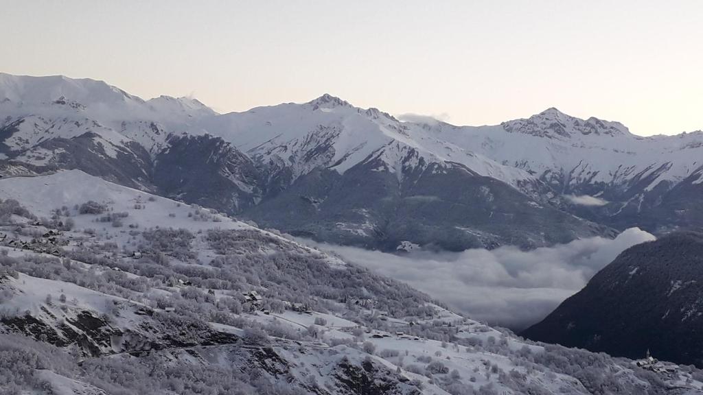 une chaîne de montagnes enneigée avec des nuages dans une vallée dans l'établissement Studio 4 personnes au pied des pistes, au Corbier