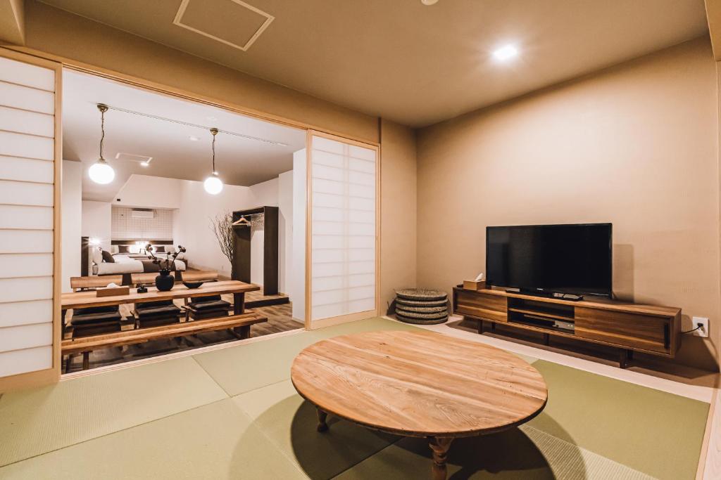 un salon avec une table et une télévision dans l'établissement Yamahana Onsen Tonden Japanese Inn, à Sapporo