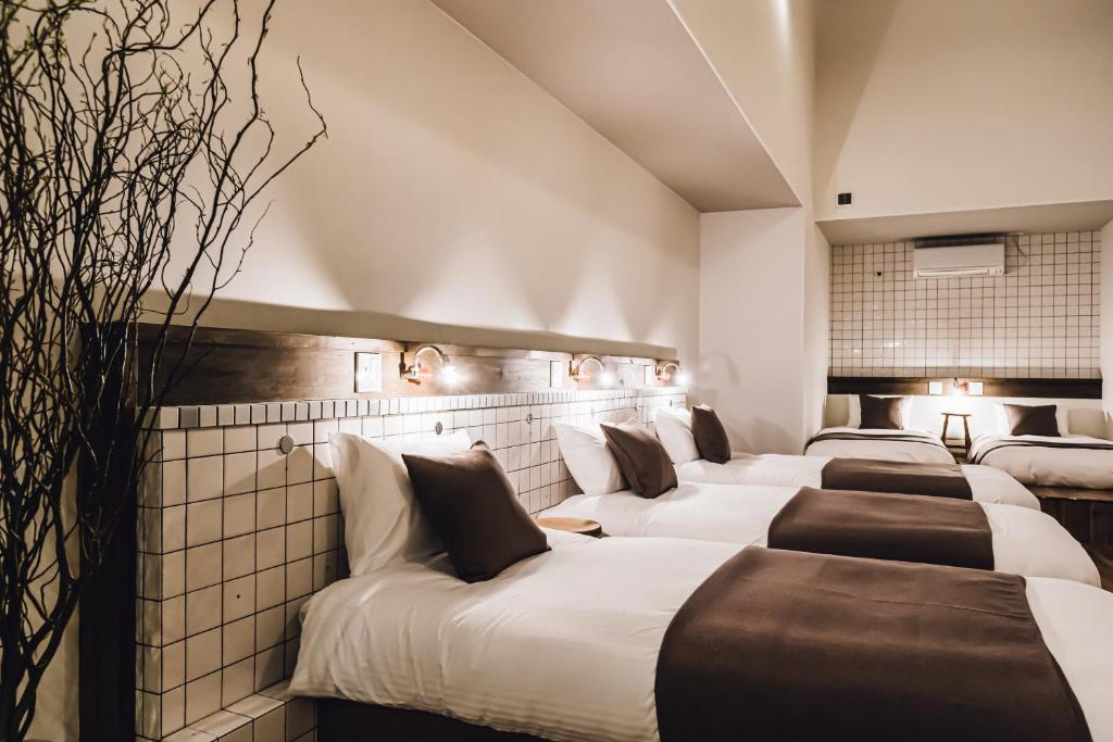 une rangée de lits dans une chambre d'hôtel dans l'établissement Yamahana Onsen Tonden Japanese Inn, à Sapporo
