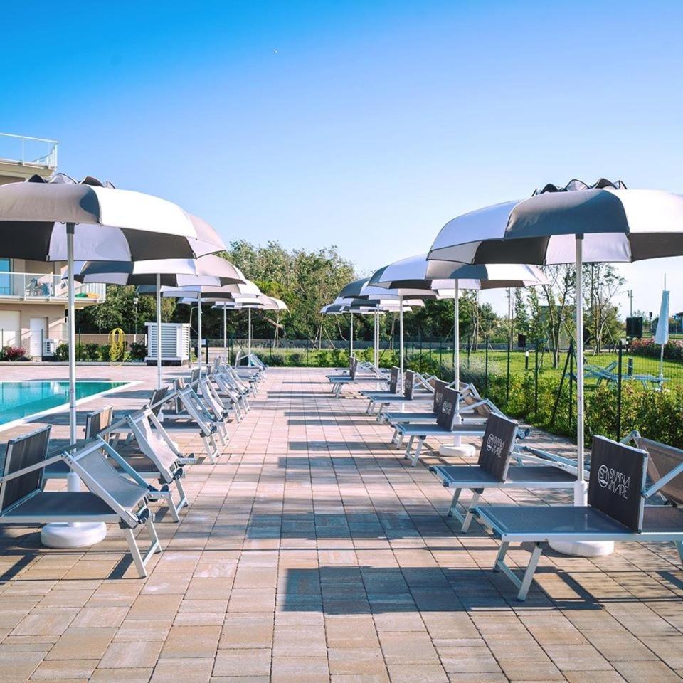 - une rangée de chaises longues avec parasols à côté de la piscine dans l'établissement Sabbia & Mare, à Rosolina Mare