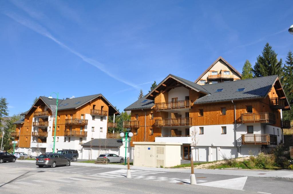 un immeuble d'appartements avec des voitures garées dans un parking dans l'établissement Vacancéole - Au Coeur des Ours, à Les Deux Alpes