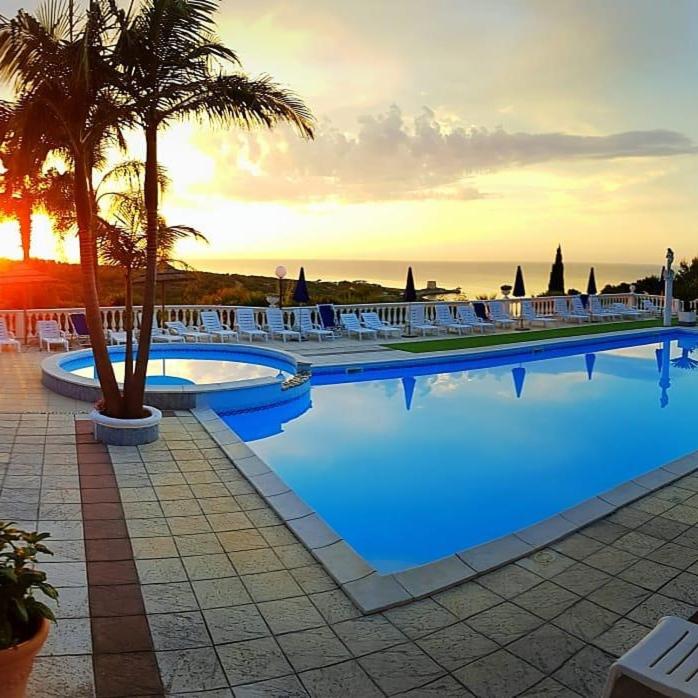 une grande piscine avec des palmiers et l'océan dans l'établissement RESIDENCE EMARINE con SERVIZIO SPIAGGIA INCLUSO, à Peschici