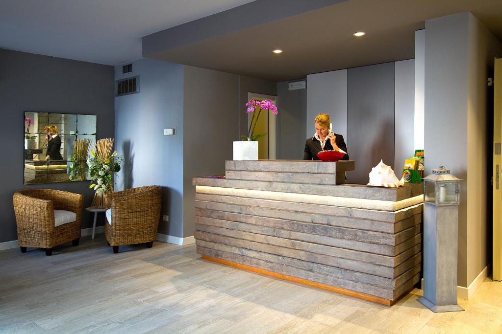 une femme assise au comptoir dans un hall dans l'établissement Aparthotel Ponza, à Lignano Sabbiadoro