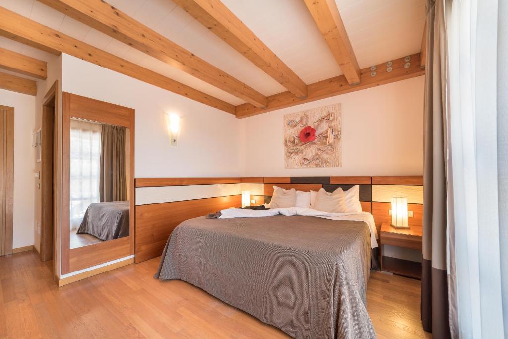une chambre avec un lit et un miroir dans l'établissement Green Village Eco Resort, à Lignano Sabbiadoro