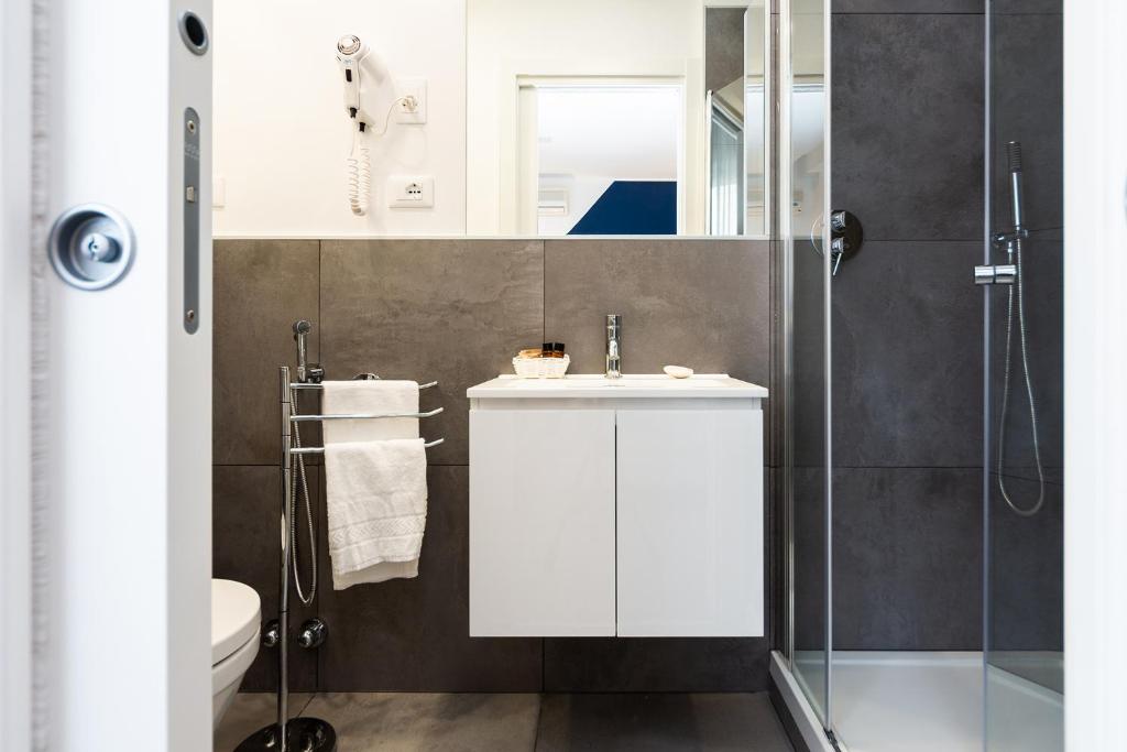 une salle de bain avec un lavabo blanc et une douche dans l'établissement Hotel Aurora, à Lignano Sabbiadoro