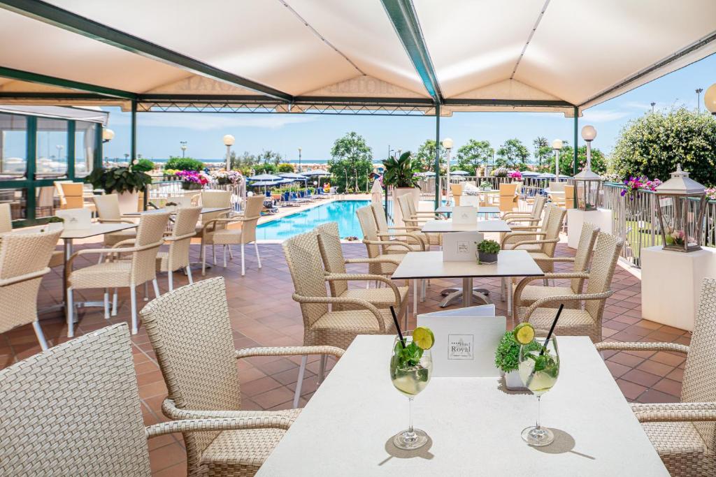 un restaurant avec des tables et des chaises et une piscine dans l'établissement Hotel Royal, à Bibione