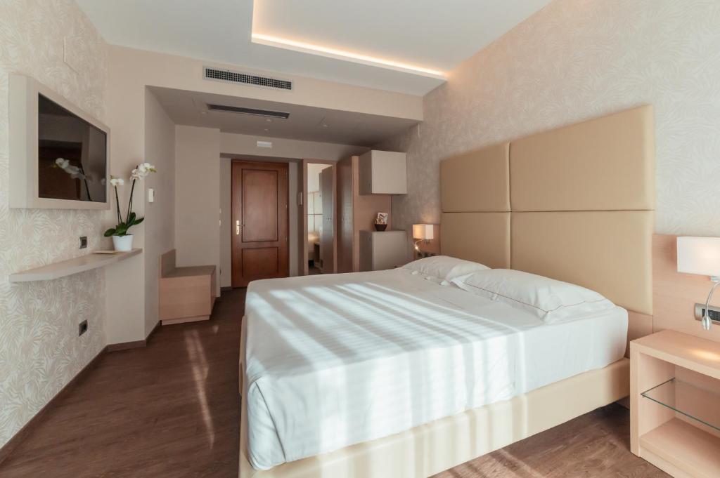 une chambre avec un grand lit blanc dans une pièce dans l'établissement Hotel Continental, à Taormine