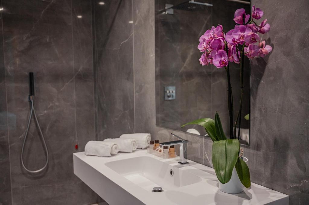 La salle de bains est pourvue d'un lavabo et d'un vase de fleurs violettes. dans l'établissement Hotel Continental, à Taormine 75 autres photos