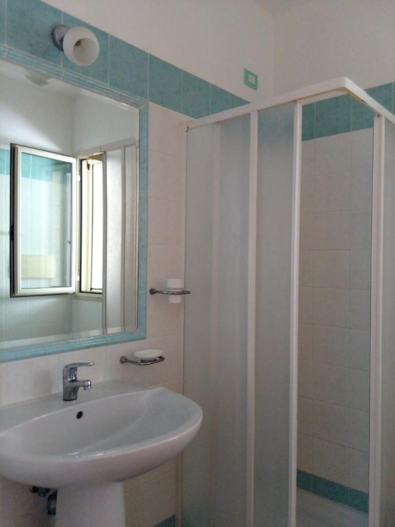une salle de bain avec un lavabo et une douche avec un miroir dans l'établissement Villa dei pini, à Vieste