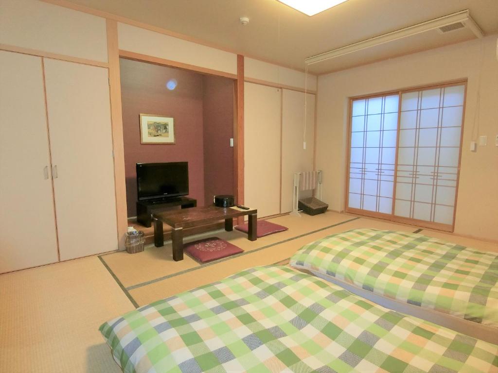 - une chambre avec 2 lits, une télévision et une table dans l'établissement Yurakuan Miyazaki, à Miyazaki