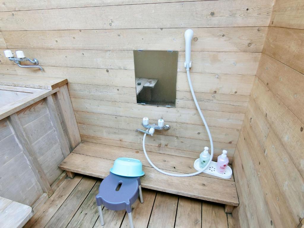 La salle de bains est pourvue d'une douche avec un tabouret bleu. dans l'établissement Yurakuan Miyazaki, à Miyazaki