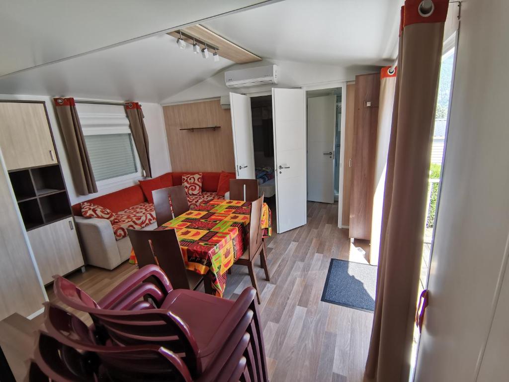 une pièce avec une table, des chaises et un canapé dans l'établissement CAMPING LE GRAND VERNEY, à Novalaise