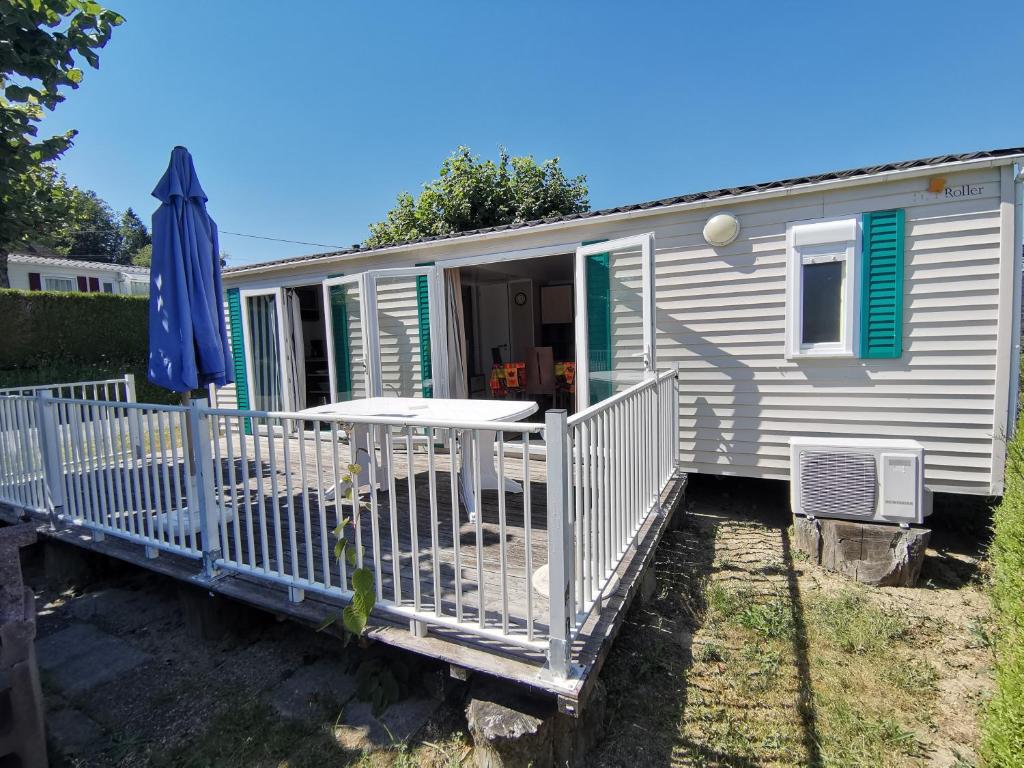 Cette petite caravane comprend une terrasse couverte et un parasol. dans l'établissement CAMPING LE GRAND VERNEY, à Novalaise