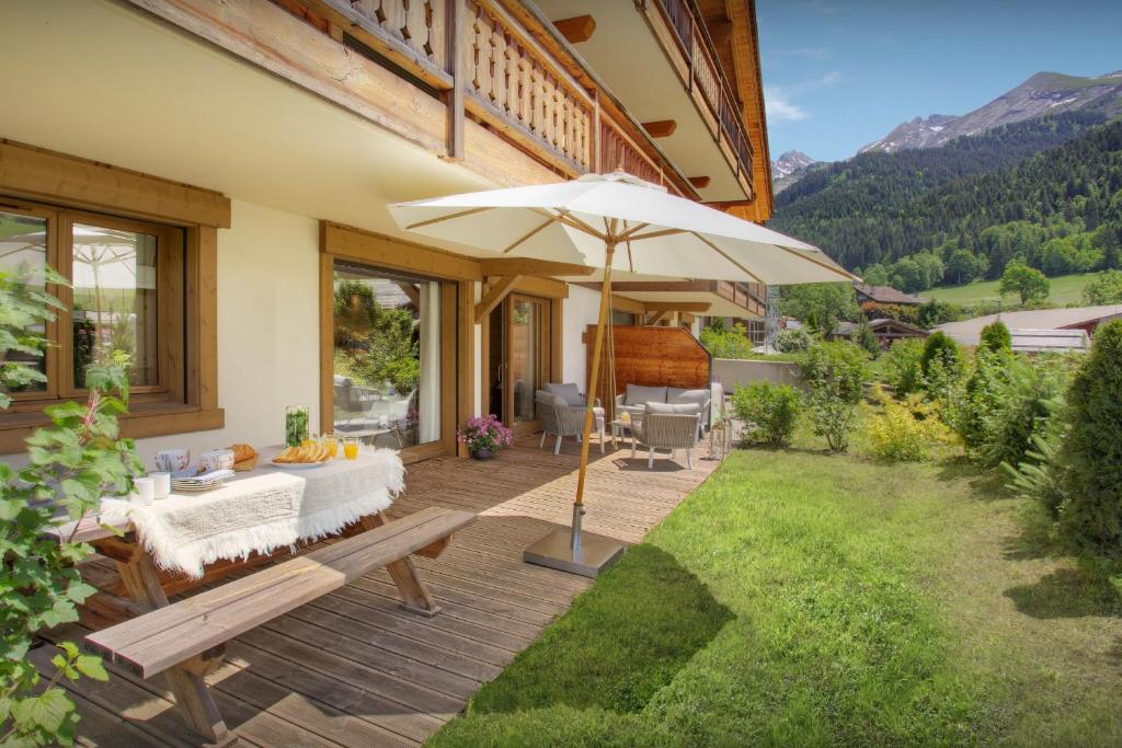 un patio avec une table et un parasol dans l'établissement Chalet Edenalpa - OVO Network, à La Clusaz