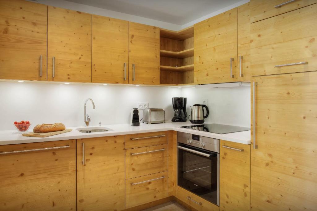 une cuisine avec des armoires en bois et un four à plaques de cuisson dans l'établissement Chalet Edenalpa - OVO Network, à La Clusaz
