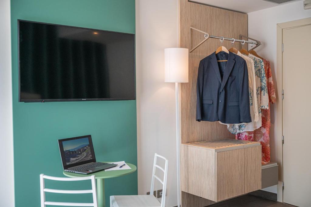 Cette chambre dispose d'un bureau et d'un ordinateur portable sur un portant. dans l'établissement Il Piccolo Giardino GH ***Superior, à Taormine