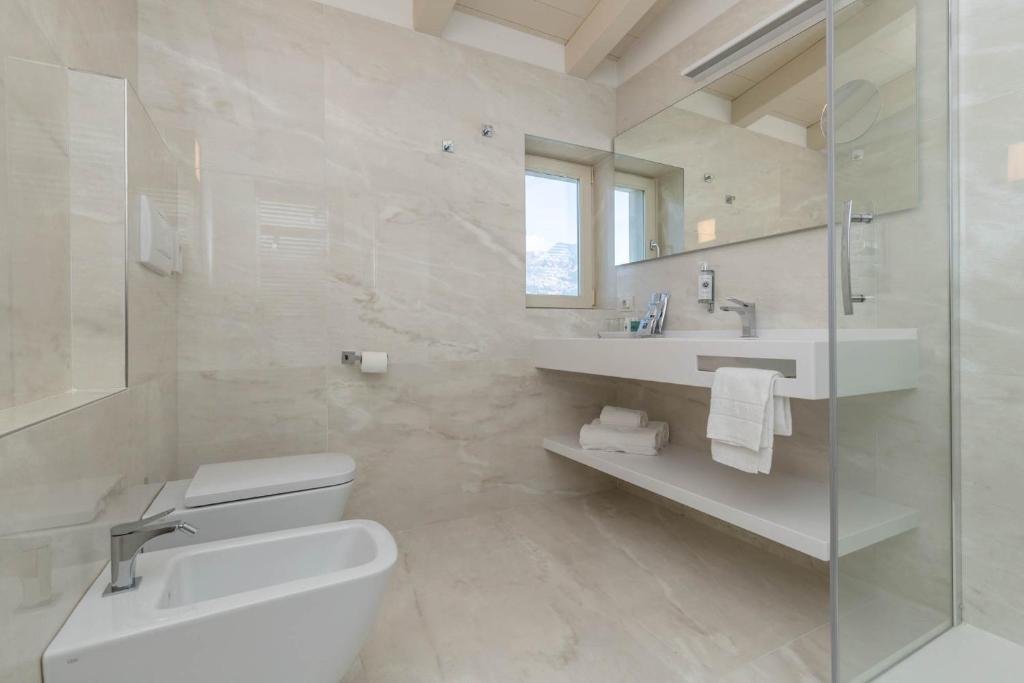 une salle de bain blanche avec un lavabo et des toilettes dans l'établissement Hotel Vega, à Malcesine