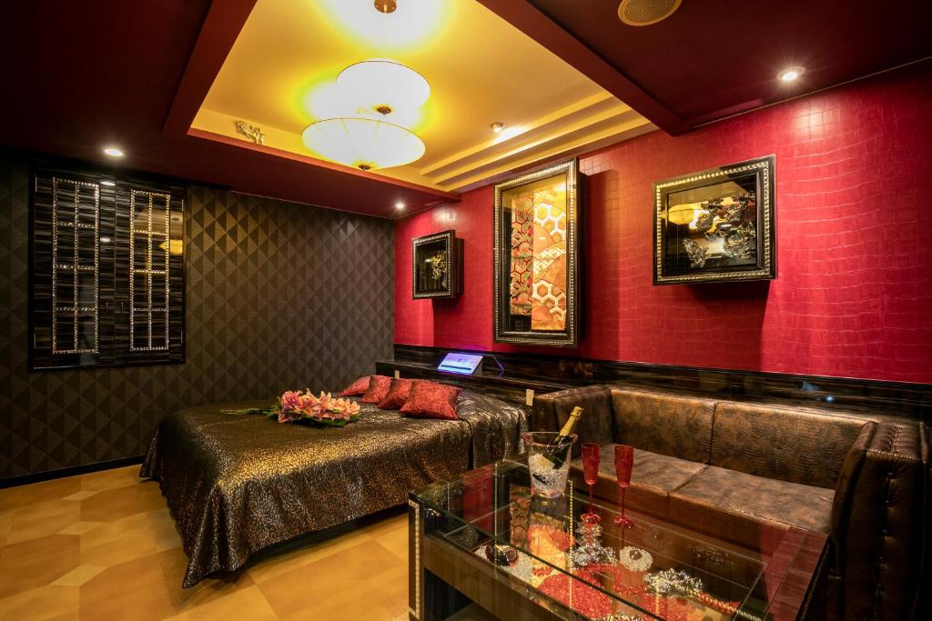 - un salon avec un canapé et des murs rouges dans l'établissement Hotel Park Inn (Adult Only), à Matsuyama
